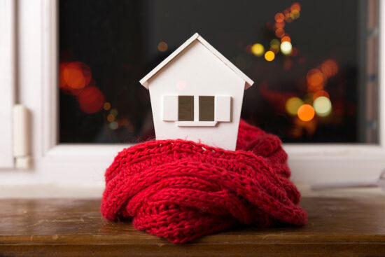 concept de système de chauffage et temps froid et neigeux avec modèle de maison portant une écharpe tricotée
