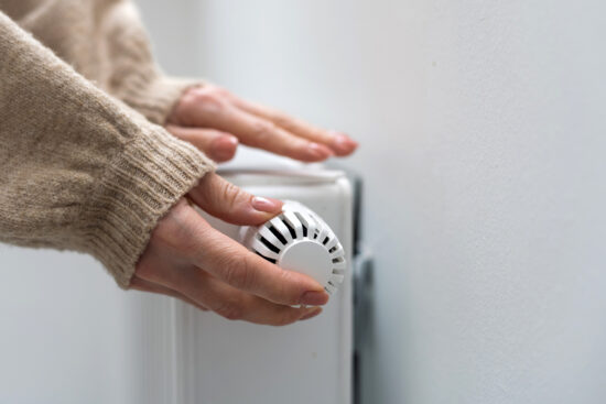 Femme tenant le  robinet thermostatique du radiateur