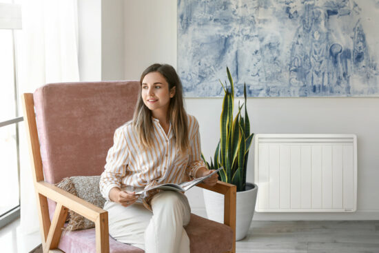 jeune femme dans un fauteuil de salon avec radiateur a inertie seche economique en arriere plan